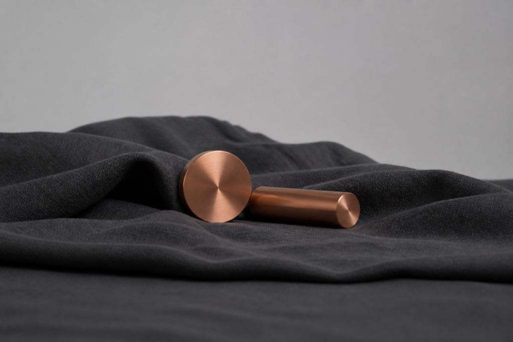 Copper metal cylinders on charcoal linen, abstract laboratory still life