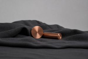 Copper metal cylinders on charcoal linen, abstract laboratory still life